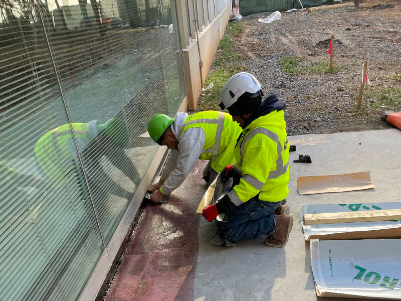 ShanCon employees working on concrete and masonry restoration waterproofing a building threshold