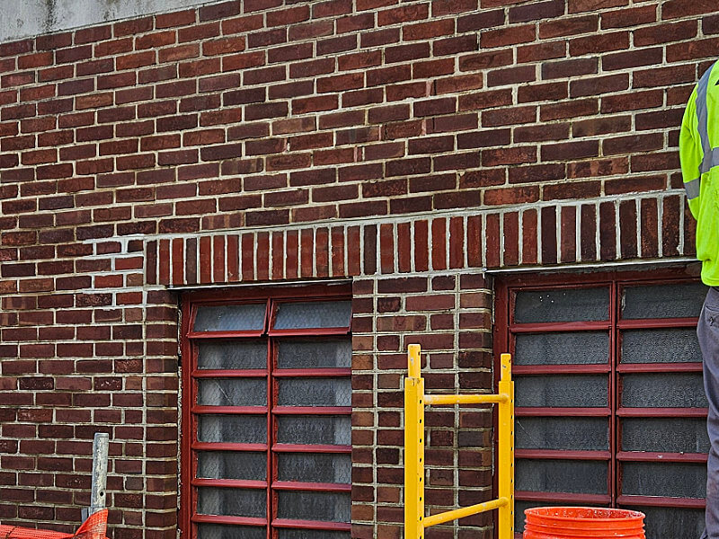 Masonry restoration and repair specialists working on a brick wall