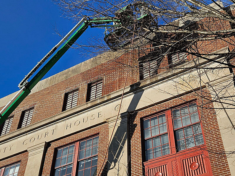 ShanCon masonry restoration specialists assessing a historic building's facade from a cherrypicker